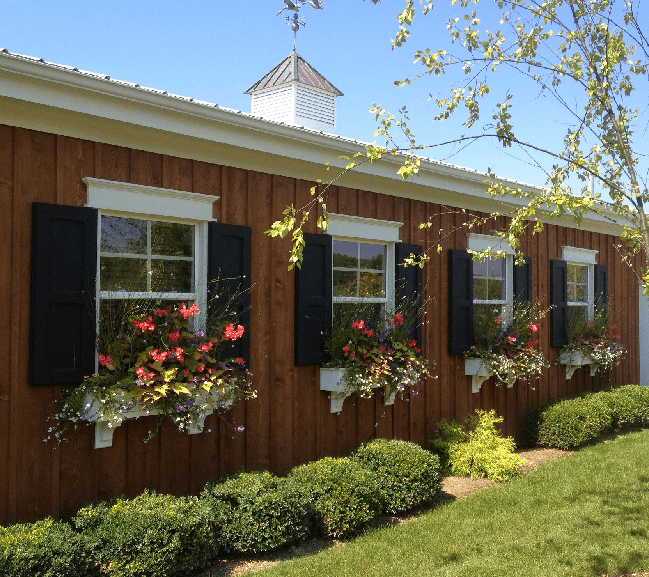 a charming wooden building with a row of windows on the side. Each window is adorned with a colorful flower box, adding a vibrant touch to the exterior